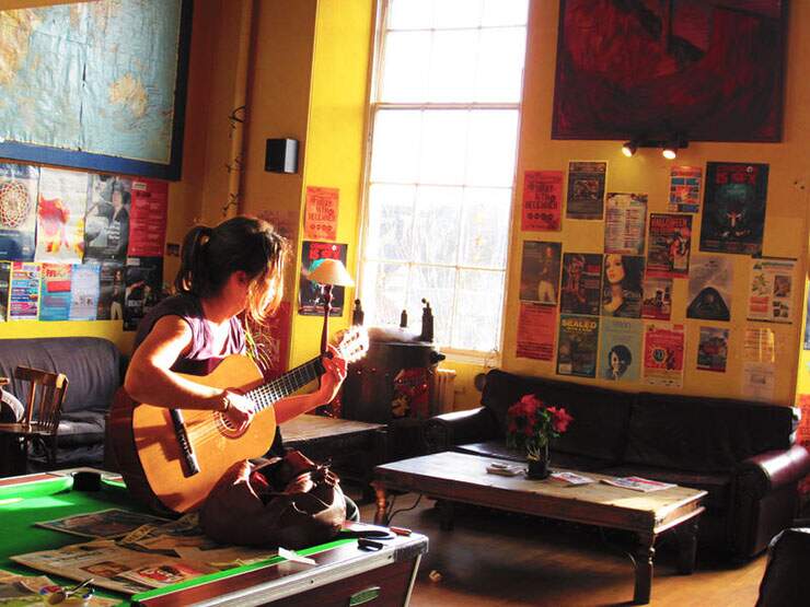 girl plays guitar on billiard table castle rock hostel