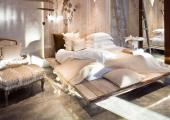 Concrete wall and floor are match with wood bed and snowy white & cream textiles
